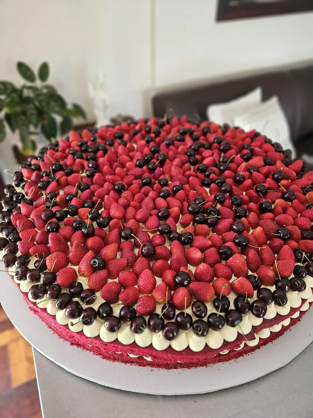 Large round wedding cake covered with raspberries, dark berries and a border of piped white icing.