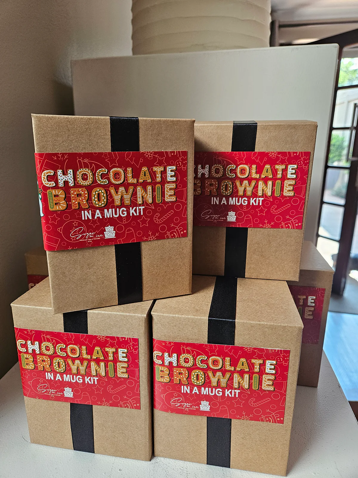 Chocolate brownie mug kits in kraft boxes with red labels and black ribbon.