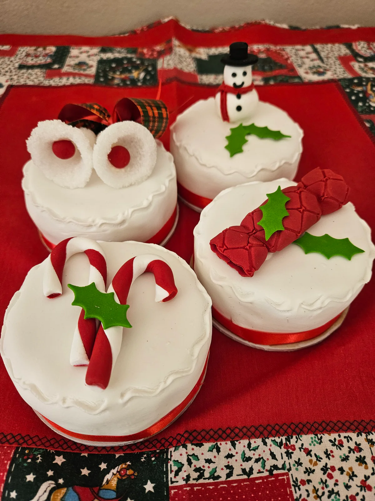 Mini white iced Christmas cakes decorated with candy canes, holly, a snowman and festive motifs.